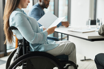 Cropped side view portrait of successful businesswoman in wheelchair reading documents at meeting...