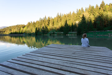 person sitting on a wooden pier