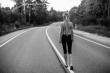 An running woman before jogging on road. Black and white photo.