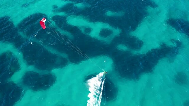 Aerial drone tracking video of kite surfer perform extreme stunts in tropical exotic island bay with emerald crystal clear sea