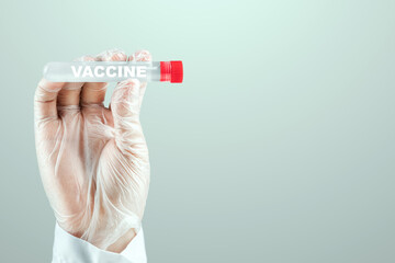 A gloved hand of a doctor holds a test tube with COVID-19 vaccine. Medical research, close-up.