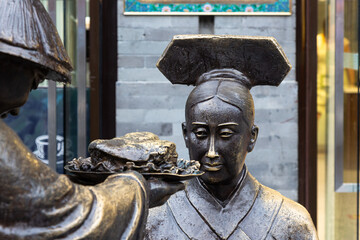 Zwei historisch gekleidete Statuen stehen in der Fußgängerzone von Peking. Die männliche Figur...