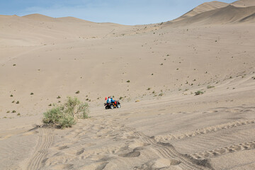 Ein Fahrzeug fährt die Dünen hoch und hinterläßt Spuren im Sand.