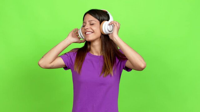 Young woman listening to music with headphones over isolated background