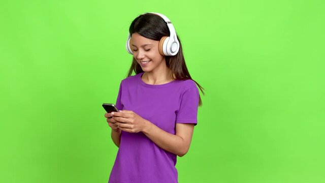 Young woman listening to music with headphones over isolated background
