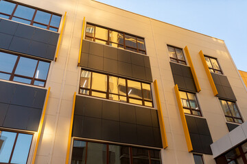 Beige and brown modern ventilated facade with windows. Fragment of a new elite residential building...