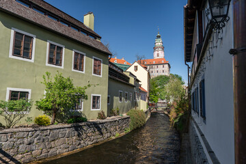Fototapeta na wymiar The Cesky Krumlov castle and tower standing guard above the town and a small river flowing through it.
