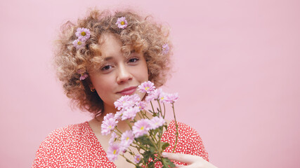 Beautiful curly hair woman enjoying the aroma of the purple spring flowers. Copy space. High quality photo
