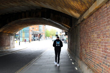Man walking through tunnel with muted light coming through the end. 