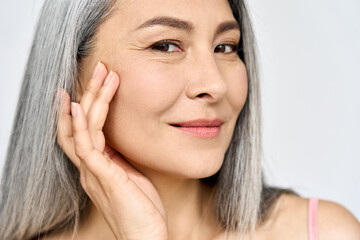 Closeup portrait of middle aged Asian woman's face with perfect skin. Older mature lady touching...