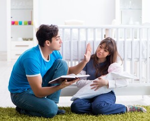 Young parents with their newborn baby sitting on the carpet