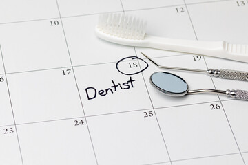 Dentist appointment reminder on calendar with toothbrush and dental tools. Concept of oral health, dental exam and teeth cleaning