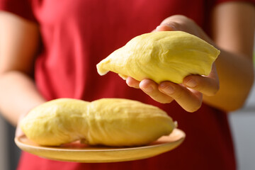 Ripe Thai durian fruit (Monthong) on wooden plate holding by woman hand, Tropical fruit