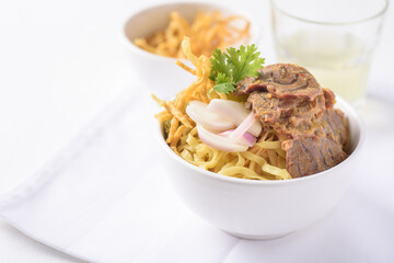 Northern Thai food (Khao soi), Spicy coconut milk curry egg noodles soup with beef in a bowl on white background