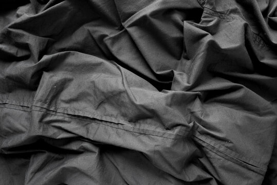unpressed dark grey black casual dress shirt with seams - photographed from above with low or raking light - emphasis on texture and folds