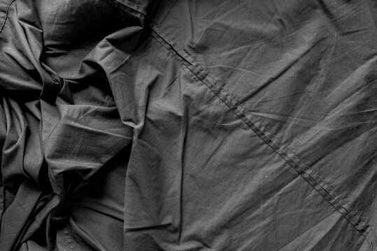 unpressed dark grey black casual dress shirt with seams - photographed from above with low or raking light - emphasis on texture and folds