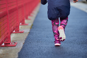 girl athlete in sportswear running young in boys' race, running in the details of the city on her legs