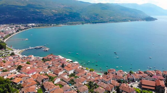 Old city of Ohrid, North Macedonia. Red roof historical medieval houses are built along side of huge lake. Beautiful antique town aerial view footage took with drone 4K 30fps.