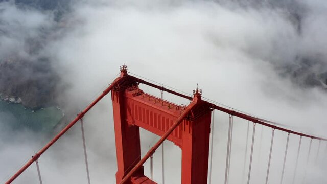 Cinematic aerial footage of fog engulfing the iconic and historic landmark the Golden Gate Bridge in San Francisco - California, USA