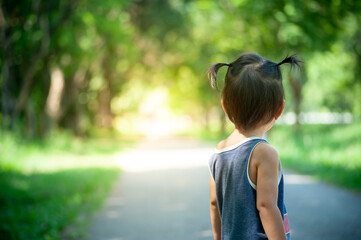 back of girl on background of road and forest park
