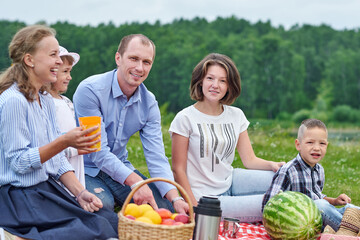Happy family at a picnic. Picnic in the meadow or park. Young friends and their children in nature
