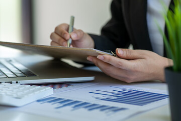 Close up of Accounting businesswoman working on note laptop computer and analyzing real estate investment data, Financial and tax systems concept.