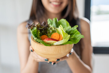 Eat high fiber and low calories foods for good health.Young woman eating bowl of fresh salad and...