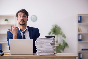 Fototapeta premium Young male employee unhappy with excessive work in the office