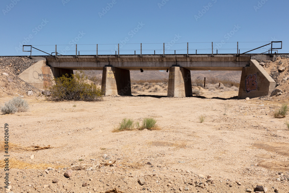 Wall mural dry wadi in the middle of the mojave desert under a blue sky