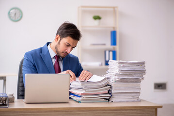 Young male employee and too much work in the office