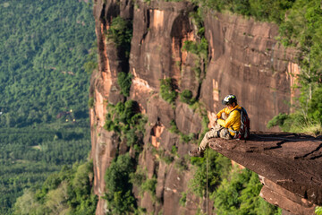 Rescue hiker with backpack climbs natural rocky wall. Wearing in climbing equipment rope carabiner