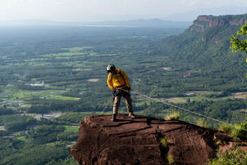 Rescue hiker with backpack climbs natural rocky wall. Wearing in climbing equipment rope carabiner