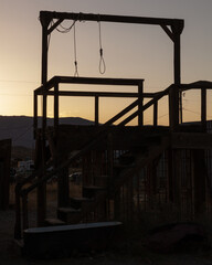 Gallows with two ropes to hang convicts, above a small cell, in an abandoned ghost town in the sunset