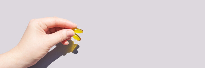 Omega3 gel capsule in hand. Sun shadow. Yellow vitamin. Health eating. Dietology drug. Fish oil...