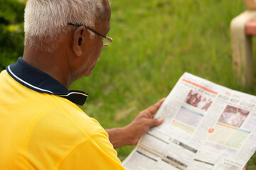 Focus on shoulder, Shoulder shot of old man busy reading morning news paper - Concept of senior people morning daily lifestyle.
