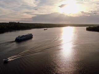 Aerial view passenger cruise ship sails along the river at sunset. Beautiful panorama of nature at sunset. Cruise trip.