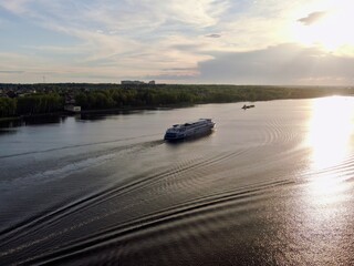 Aerial view passenger cruise ship sails along the river at sunset. Beautiful panorama of nature at sunset. Cruise trip.