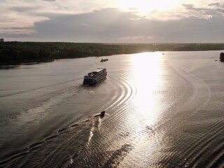 Aerial view passenger cruise ship sails along the river at sunset. Beautiful panorama of nature at sunset. Cruise trip.