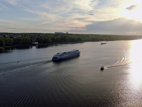 Aerial view passenger cruise ship sails along the river at sunset. Beautiful panorama of nature at sunset. Cruise trip.