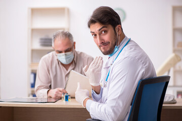 Obraz premium Old male patient visiting young male doctor in vaccination conce