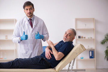 Fototapeta premium Old male patient visiting young male doctor in vaccination conce