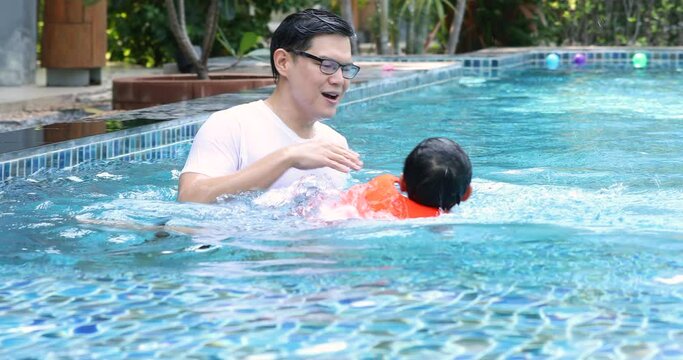 Asian father with little son in swimmingpool at park. Family Leisure and travel at holidays...