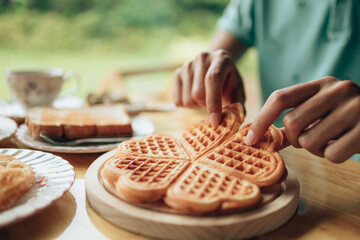 Hand pick  piece fresh waffles on wood plate. Waffle and dessert concept.