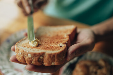 Knife spreading butter on toast bread in hands in the morning breakfast. Coffee and dessert concept.