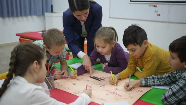 Teacher and collective of elementary age children draw together a board game