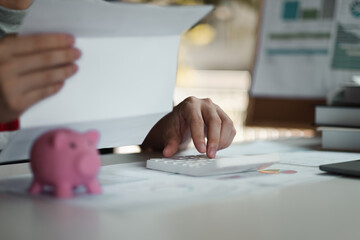 Woman calculating her Debt. woman hand calculating her monthly expenses during tax season with coins, calculator and account bank.