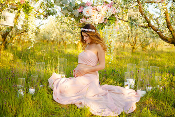 Cute pregnant belly outside. Young pregnant woman embracing her naked abdomen with hands outdoor. Big belly on the third trimester of pregnancy close-up. Concept of happy pregnant life.