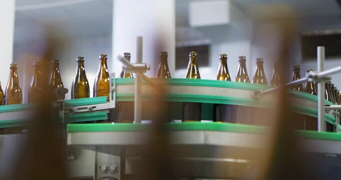 Glass beer bottles in factory or brewery on conveyor belt, artistic view
