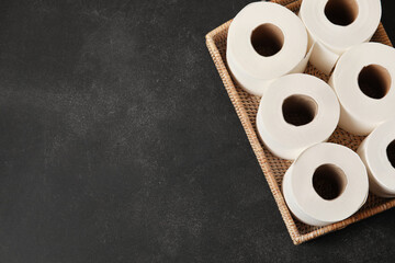 Basket with rolls of toilet paper on dark background