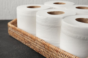 Basket with rolls of toilet paper on table, closeup